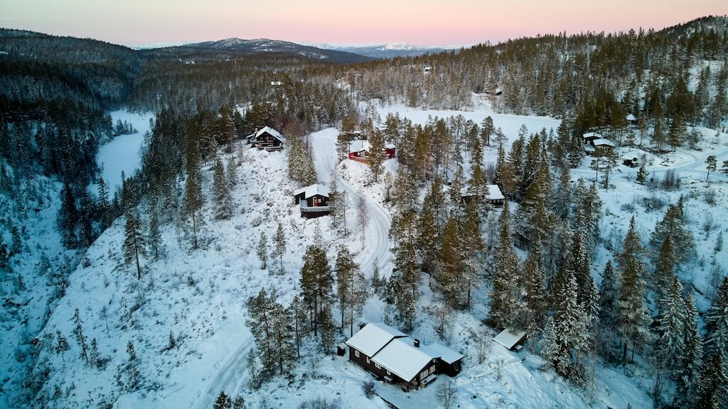 Snødekt hytteområde i skogen sett ovenfra